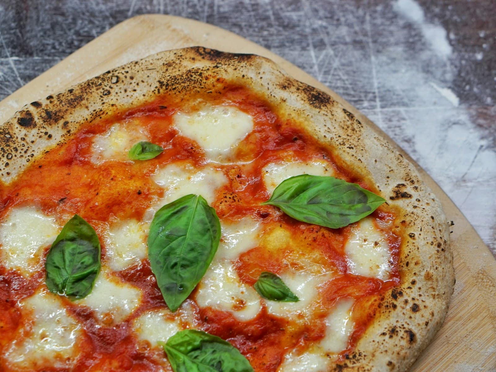 Hands shaping a round of fresh pizza dough